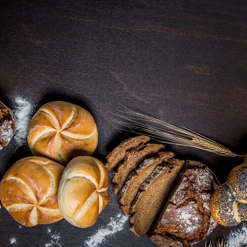 Assorted artisanal breads arranged along a dark wooden surface