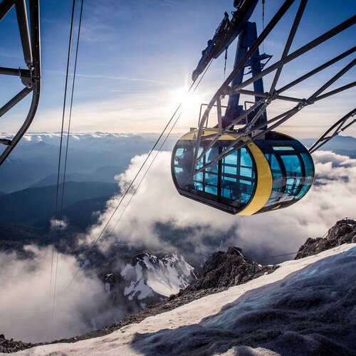 Cable car gondola suspended above snow and clouds on a mountain