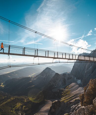 Suspension bridge across a rocky mountain valley with hiker