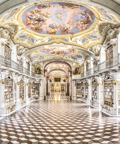 Ornate baroque library with arches, gilded decorations, and checkered floor