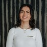 Smiling young woman wearing white long-sleeve shirt with small logo on chest