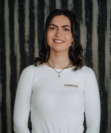 Smiling young woman wearing white long-sleeve shirt with small logo on chest
