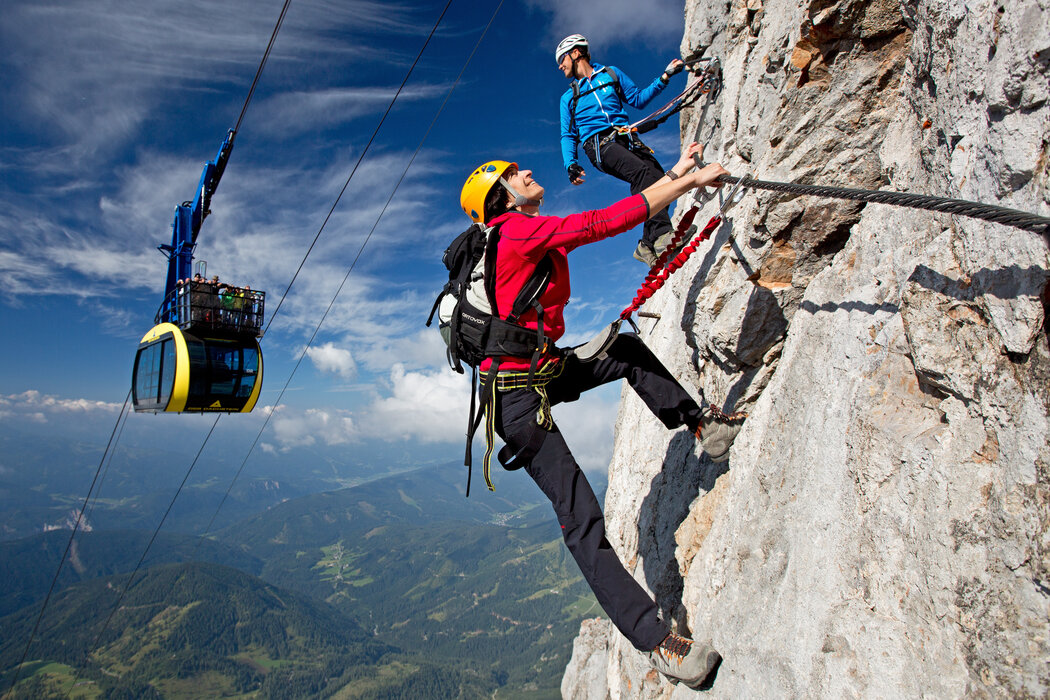 Two climbers on a rock face with a cable car nearby | © HERBERT RAFFALT