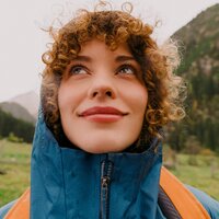 Person with curly hair wearing blue rain jacket outdoors