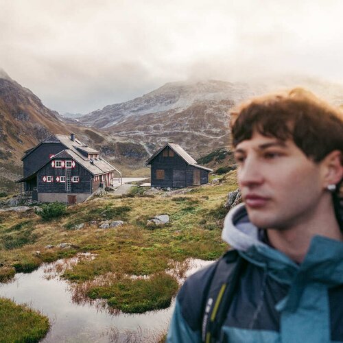 Young man in foreground with alpine huts and mountains