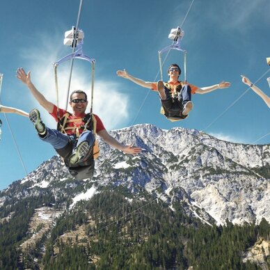 Four people ziplining above a mountainous landscape