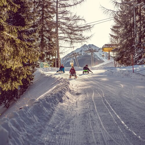 Three people sledding down a snowy mountain slope