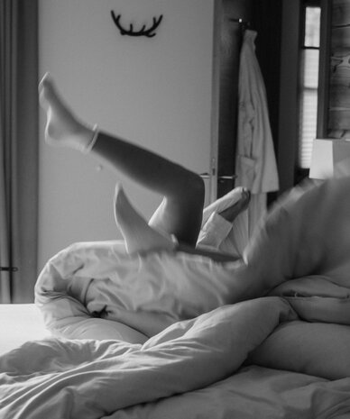 Person on bed raises leg in mid air in bedroom