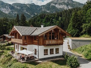 Alpine wooden chalet with guests on a patio