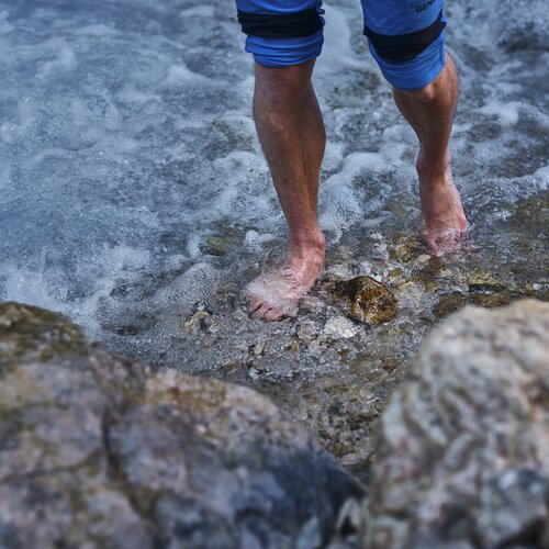 Bare feet stepping into clear rocky water | © RAPHAELGABAUER.COM