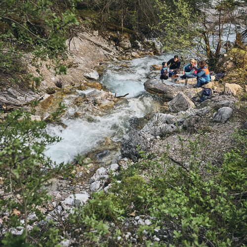 Group of hikers around campfire by a mountain river | © RAPHAELGABAUER.COM