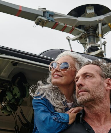Two adults leaning from open helicopter door, gazing outward