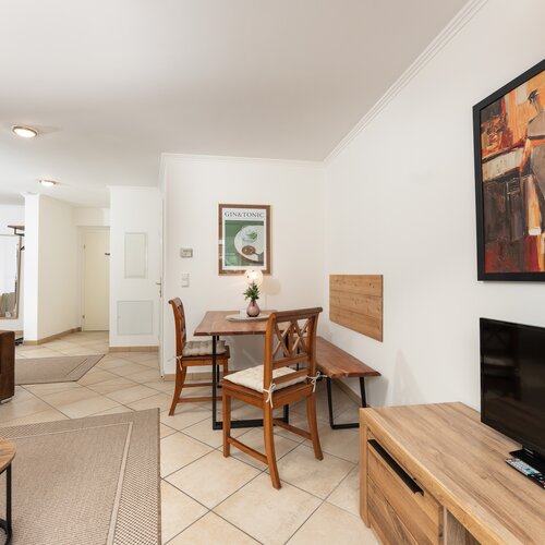 Wohnzimmer mit brauner Couch, holzfarbener Esstisch, Kunstwerk.