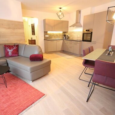 Open-plan living room with grey sofa, dining area, and kitchen