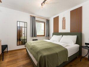 Bedroom with green upholstered bed, wood slat panels, and mirror
