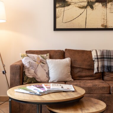 Cozy living room with brown sofa, coffee tables, and artwork.