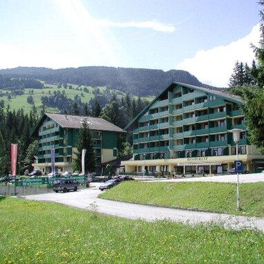 Two green alpine hotels with restaurant sign and welcome banners