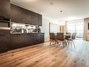 Open-plan kitchen with dark cabinets and dining table