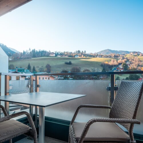 Balcony seating area with two wicker chairs and a table, overlooking countryside | © TIEBER