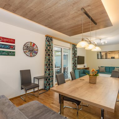 Open living and dining area with teal sofa and coffee wall art