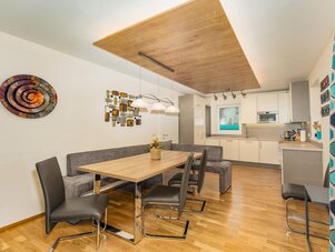 Heller offener Essbereich mit Holztisch und Küche.