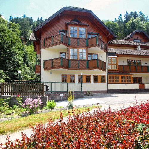 Chalet-style building with multiple wooden balconies surrounded by trees