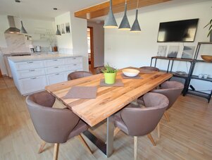 Wooden dining table with six brown chairs in open-plan kitchen.