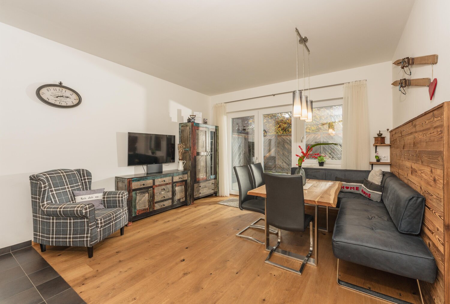 Living room with dining table, sofa, plaid armchair, and rustic sideboard
