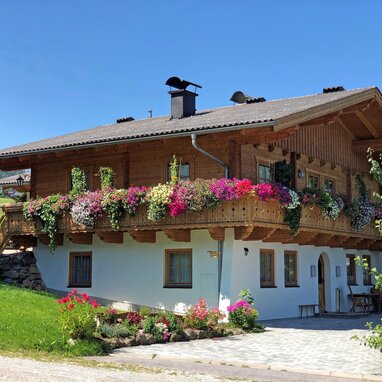 Two-story wooden chalet with colorful flower-filled balcony
