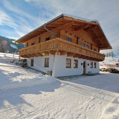 Holzhaus im Alpenstil mit verschneiter Umgebung und Balkon