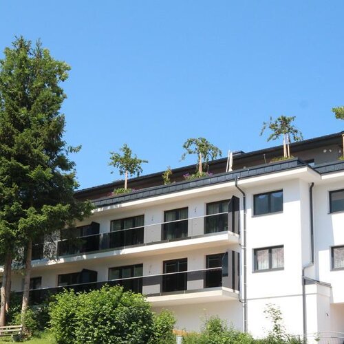 Moderner weißer Wohnhauskomplex mit Balkonen und Bäumen