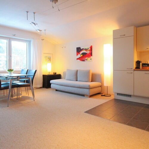 Bright open-plan living space with sofa, dining table, and kitchen.