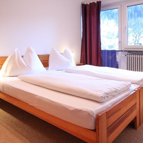 Double bed with white linens and wooden frame in hotel room