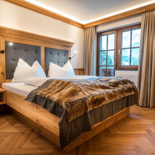 Wooden bed with tufted headboard and fur throw