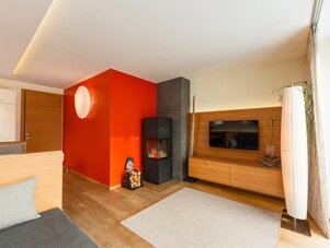 Wohnzimmer mit roter Akzentwand, Kamin und TV-Anlage