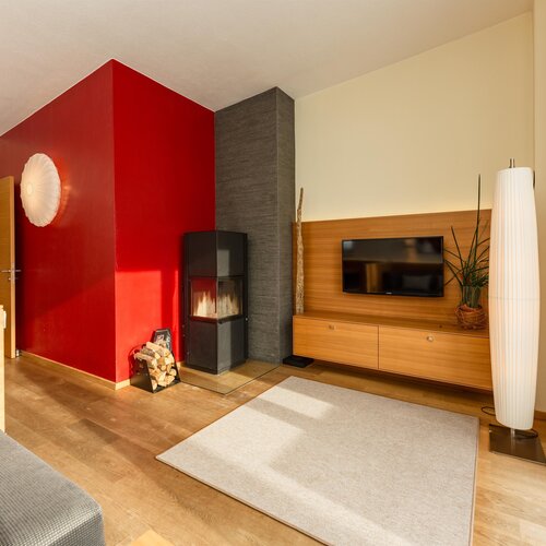 Modernes Wohnzimmer mit roter Akzentwand, Kamin und TV