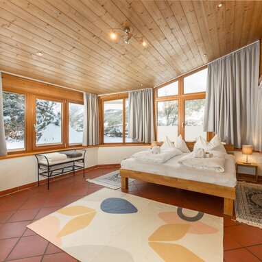 Cozy wooden bedroom with large windows and bed