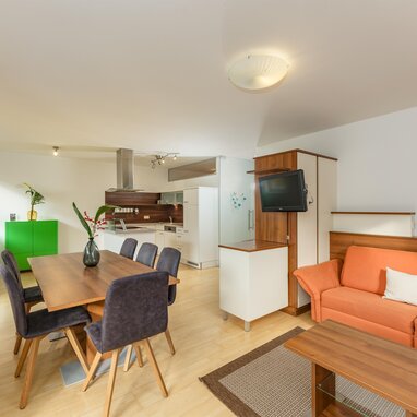 Open-plan living area with orange sofa and dining table