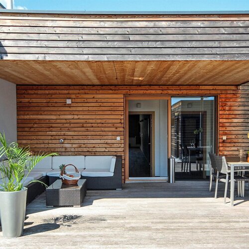 Holzverkleidete Terrasse mit Sitzgelegenheit und Essbereich