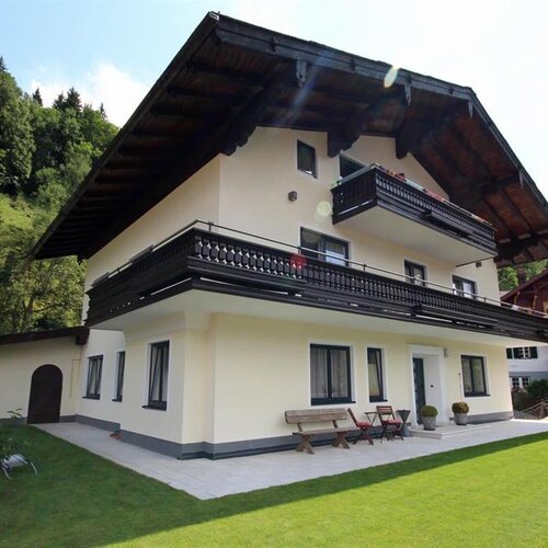 Dreistöckiges Alpenhaus mit breiten Balkonen auf grünem Rasen