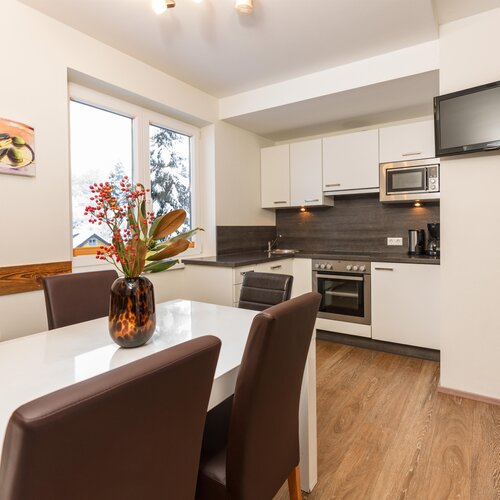 Moderne Küche mit weißer Front, Esstisch und TV