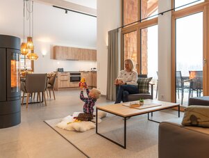 Child playing with toy on fluffy rug as woman sits nearby