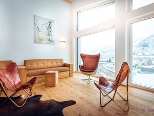 Bright living room with leather chairs and large windows overlooking snowy mountains