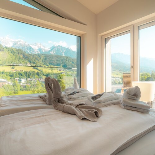 Modern bedroom with mountain view and folded towels on bed | © TIEBER