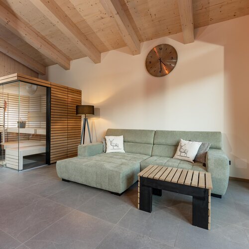 Living room with green sectional sofa and glass sauna