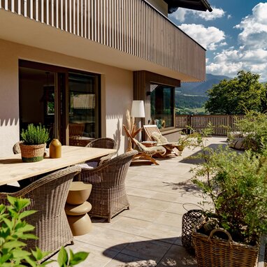 Terrace with wooden table, wicker chairs, and potted plants