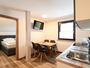 Offener Raum mit Küche, Esstisch und Blick ins Schlafzimmer.