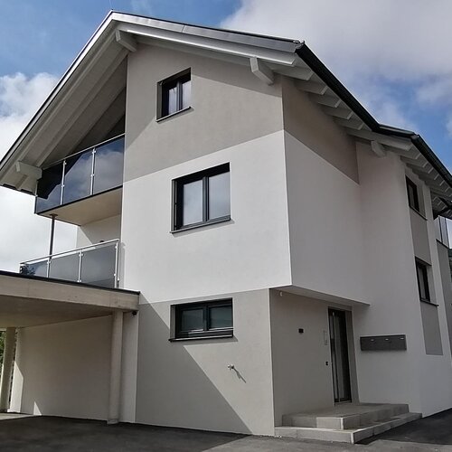 Modern multi-story white house with driveway and carport