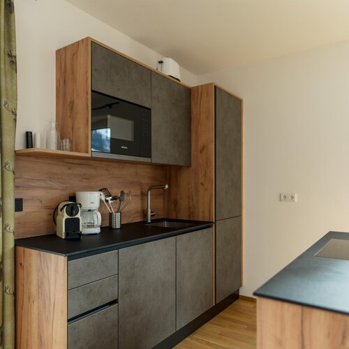 Modern kitchen with wood and gray cabinets, sink, microwave, and coffee maker.