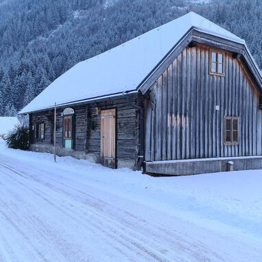 Verschneite ländliche Hütte mit Holzwänden in Berglandschaft